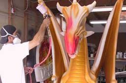 Worker spraying foam dragon sculpture