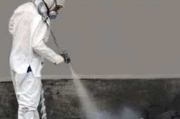Worker spraying material on flooring